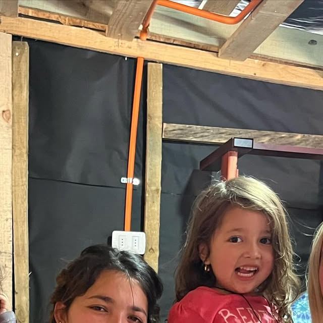 Niñas frente a una casa de madera, ayuda a una familia afectada por un incendio
